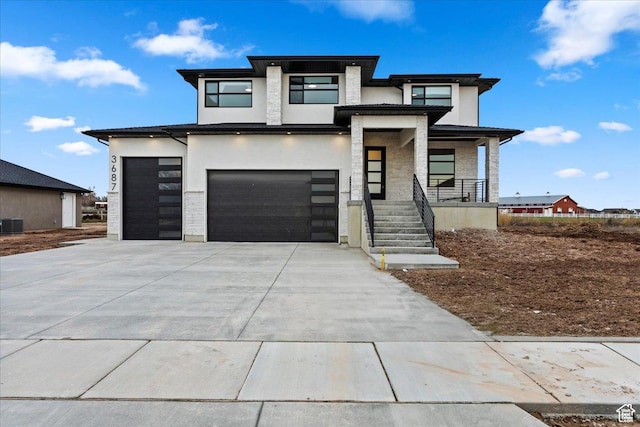 view of front of house with covered porch, stucco siding, a garage, stone siding, and driveway