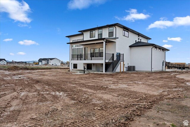 rear view of property featuring stairs, central AC, and stucco siding