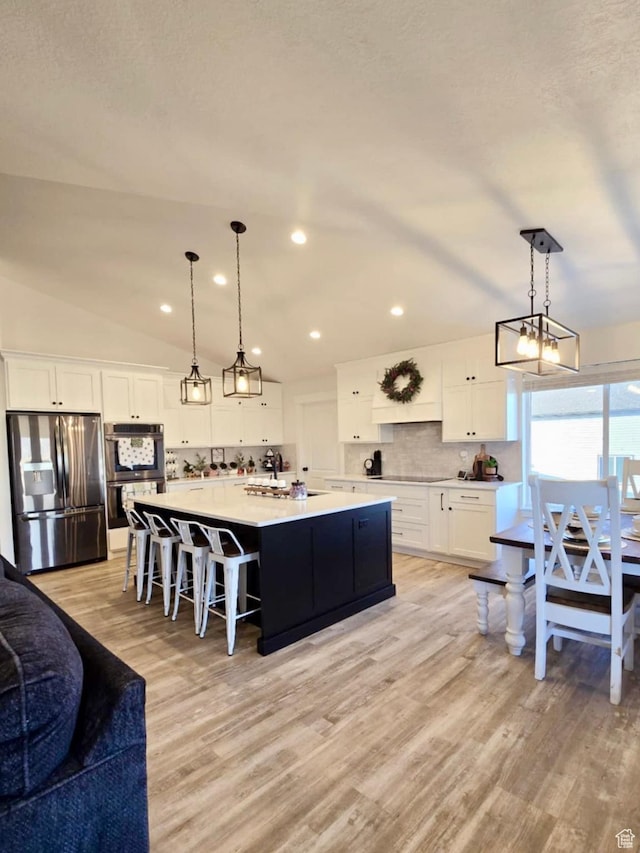9480 N 5600 W, Elwood, UT 84337 - kitchen featuring lofted ceiling, white cabinets, light wood-style floors, decorative backsplash, and stainless steel appliances