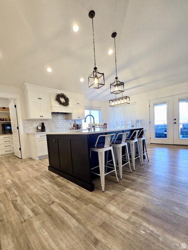 9480 N 5600 W, Elwood, UT 84337 - kitchen featuring white cabinets, light wood finished floors, a breakfast bar, and decorative backsplash