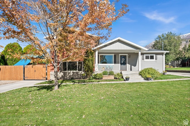 view of front facade with driveway, a front lawn, a gate, a porch, and fence