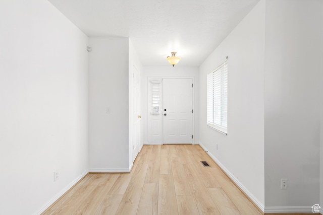 entryway with visible vents, light wood-style flooring, and baseboards