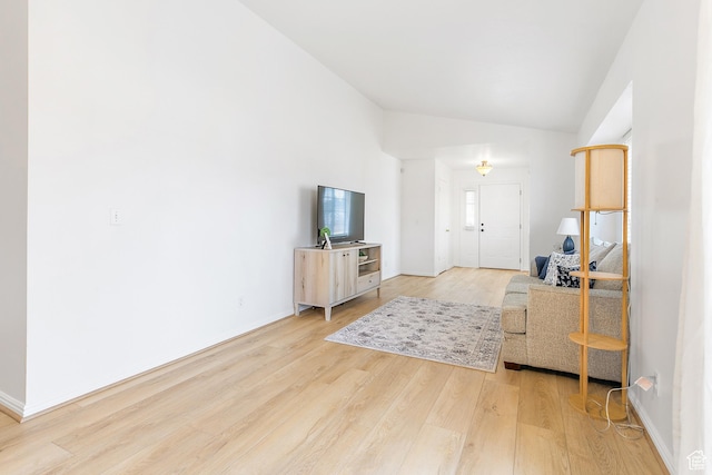 living room featuring baseboards, light wood finished floors, and vaulted ceiling