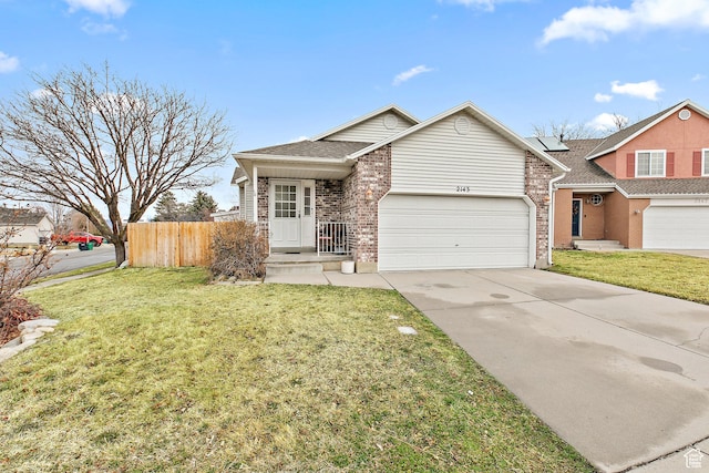 view of front of property featuring a front lawn, driveway, fence, an attached garage, and brick siding