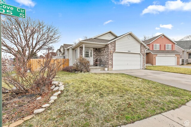 view of front of house featuring brick siding, concrete driveway, a front yard, and fence