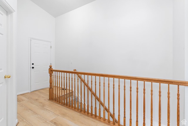corridor with an upstairs landing and wood finished floors