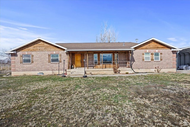rear view of house with brick siding, a carport, a yard, and covered porch