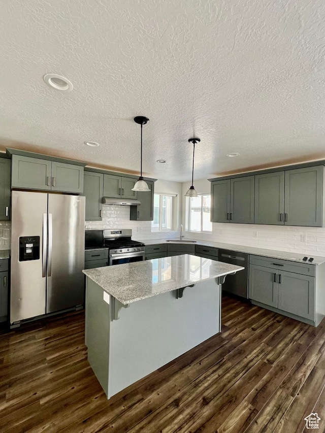 kitchen featuring a sink, stainless steel appliances, tasteful backsplash, and dark wood finished floors