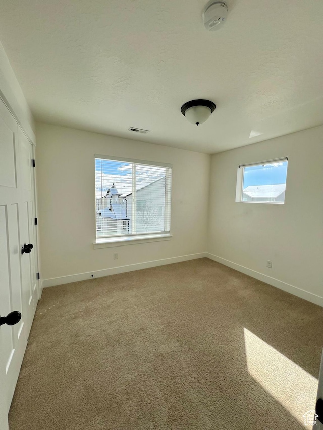 empty room featuring visible vents, baseboards, carpet, and a textured ceiling