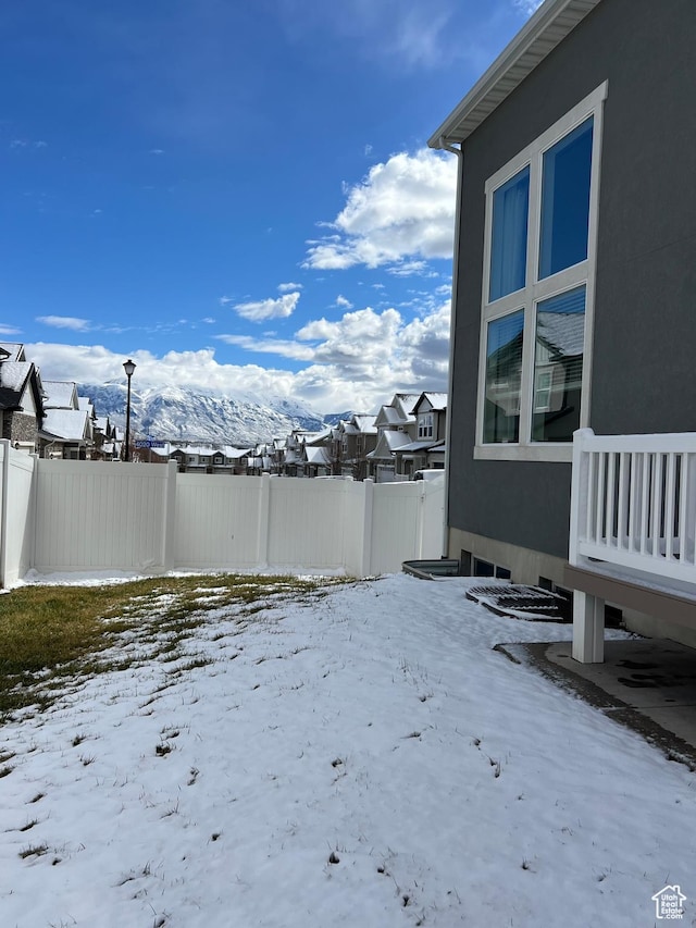 snowy yard with a residential view and fence