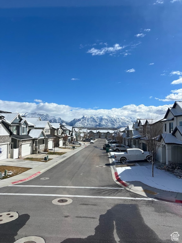 view of road with curbs, a mountain view, a residential view, and sidewalks