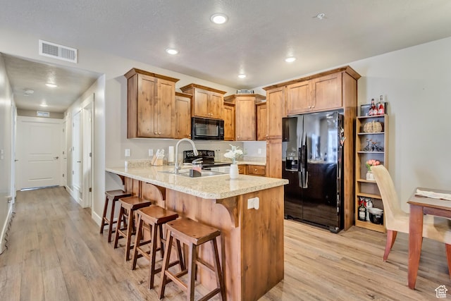 1128 S 820 E Unit 6104, Heber City, UT 84032 - kitchen with visible vents, black appliances, a kitchen breakfast bar, light wood-style floors, and a peninsula