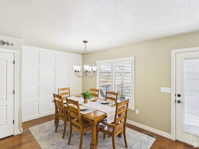 dining area featuring a textured ceiling, visible vents, a chandelier, and dark wood finished floors