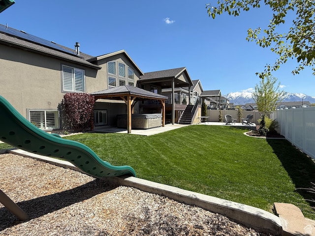 view of yard with a playground, a gazebo, a patio area, a hot tub, and a fenced backyard