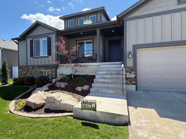 view of front facade with a porch, concrete driveway, stone siding, and board and batten siding