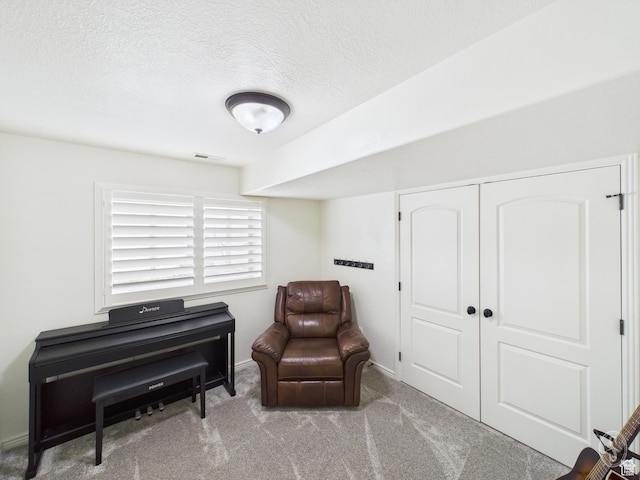 sitting room with a textured ceiling, visible vents, baseboards, and carpet floors