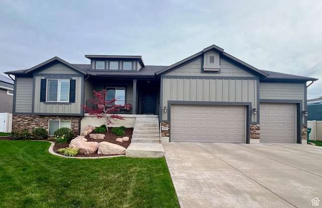 craftsman inspired home featuring covered porch, a garage, stone siding, a front yard, and concrete driveway