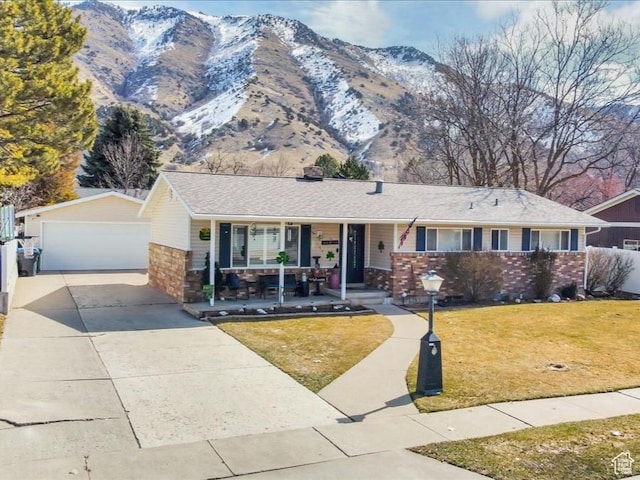 ranch-style house featuring a front lawn, covered porch, a garage, an outbuilding, and a mountain view