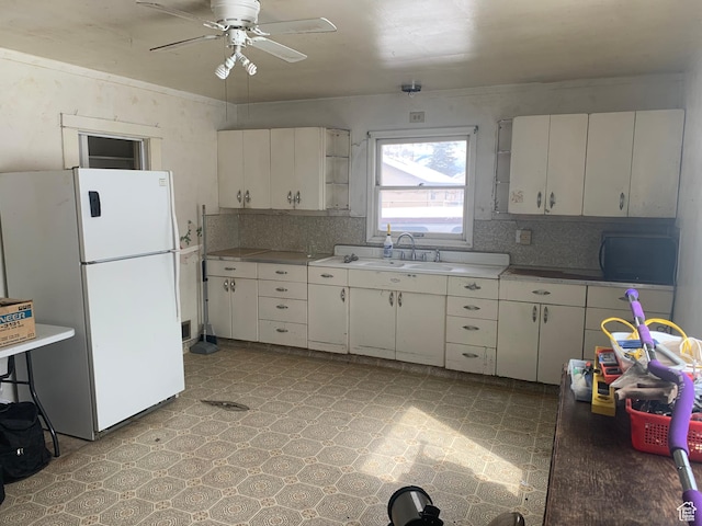 kitchen featuring a sink, freestanding refrigerator, light countertops, light floors, and ceiling fan