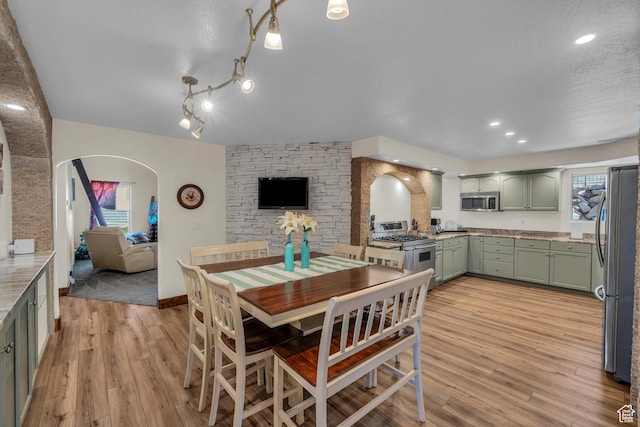 1060 E Summit Ridge Dr, St George, UT 84790 - dining space with baseboards, arched walkways, light wood-style flooring, and track lighting