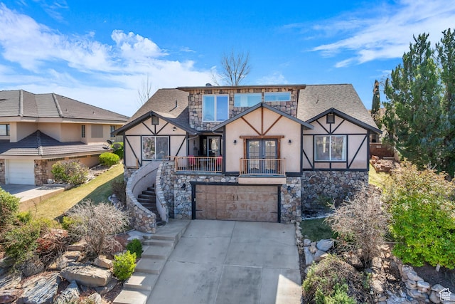 tudor home with stucco siding, stone siding, concrete driveway, an attached garage, and stairs