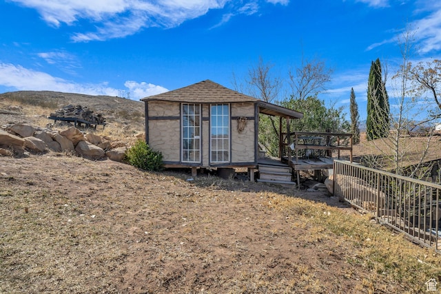 1060 E Summit Ridge Dr, St George, UT 84790 - exterior space with stone siding, fence, a mountain view, roof with shingles, and an outdoor structure