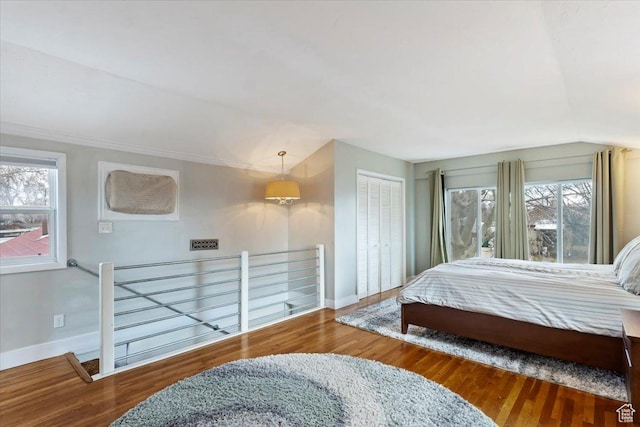 bedroom featuring a closet, lofted ceiling, baseboards, and wood finished floors