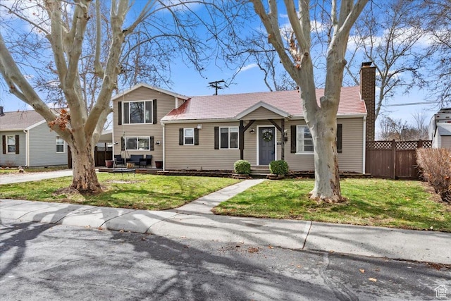 split level home with a front lawn, a chimney, and fence