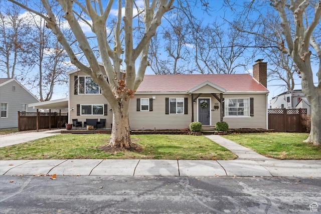 view of front of house with a carport, concrete driveway, a front yard, and fence