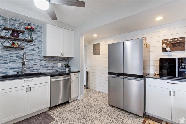 kitchen with dark countertops, ceiling fan, appliances with stainless steel finishes, white cabinets, and a sink