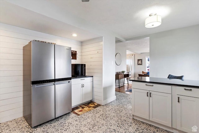 kitchen featuring dark countertops, wood walls, and freestanding refrigerator