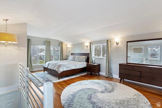 bedroom featuring vaulted ceiling, multiple windows, a notable chandelier, and wood finished floors