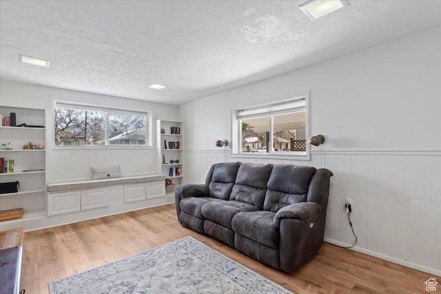 living area featuring a wainscoted wall, a textured ceiling, and wood finished floors