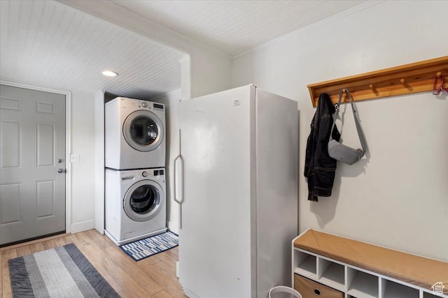 laundry area with laundry area, light wood-style flooring, stacked washer / drying machine, and ornamental molding