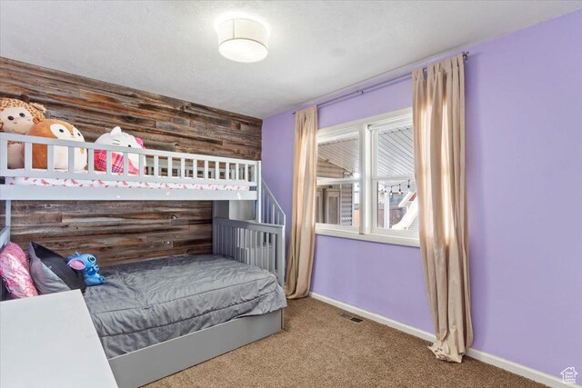 carpeted bedroom featuring visible vents, wood walls, and baseboards