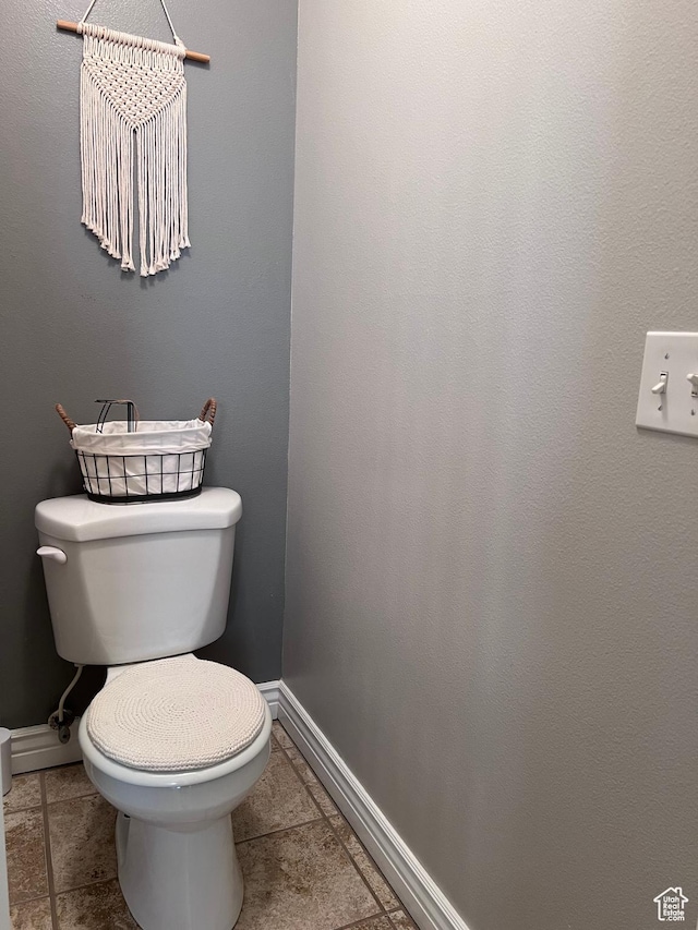 bathroom with baseboards, tile patterned floors, and toilet