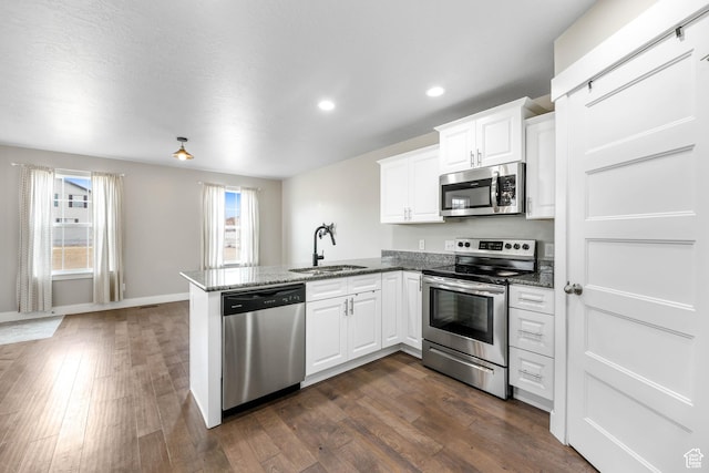 1848 E American Way Unit 2, Eagle Mountain, UT 84005 - kitchen with stainless steel appliances, a sink, a peninsula, dark wood finished floors, and white cabinetry