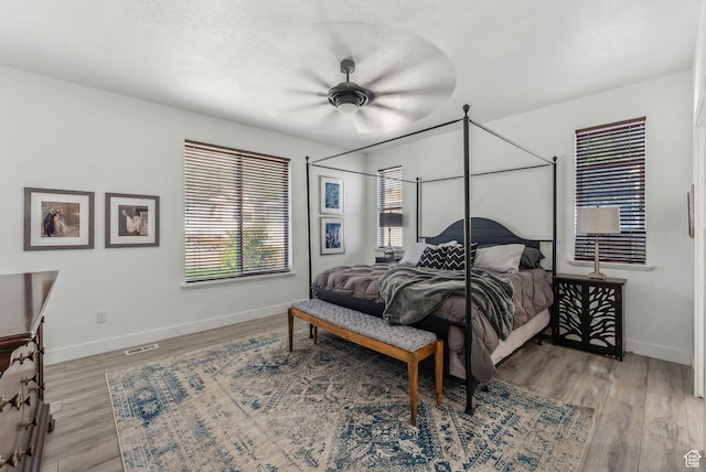 bedroom featuring baseboards, light wood-style floors, and a ceiling fan