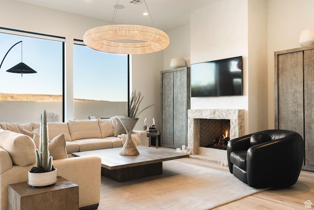 living area with a high end fireplace, visible vents, recessed lighting, a high ceiling, and wood finished floors