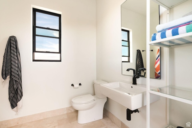 bathroom with a sink, baseboards, and toilet
