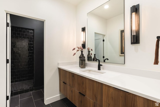 bathroom featuring tile patterned flooring, tiled shower, and vanity