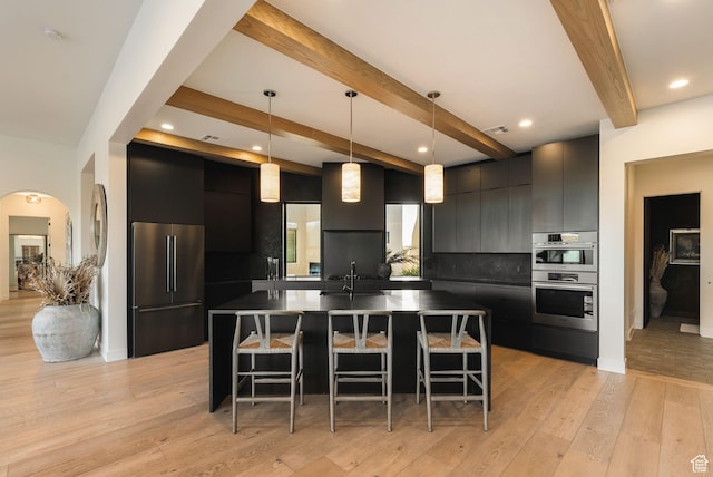 kitchen featuring a kitchen bar, appliances with stainless steel finishes, modern cabinets, and dark cabinetry