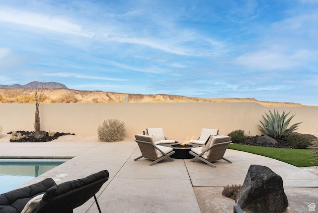 view of patio with fence, a mountain view, and an outdoor fire pit