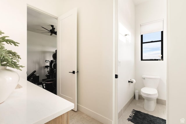 bathroom with tile patterned flooring, toilet, baseboards, and ceiling fan