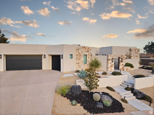 pueblo-style home featuring stucco siding, driveway, and a garage