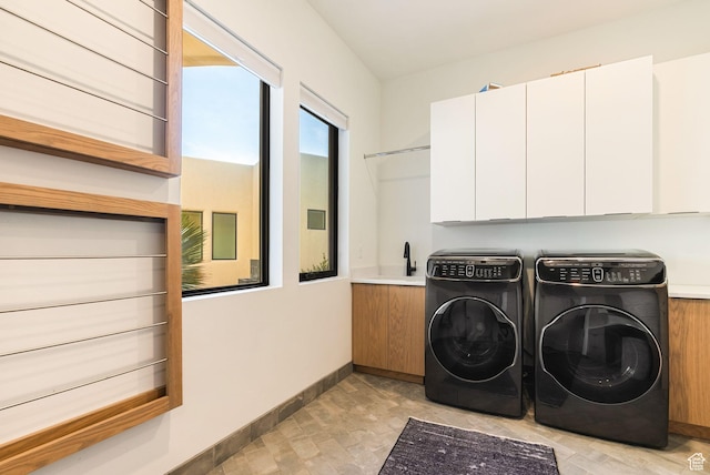 laundry area featuring cabinet space, washer and dryer, baseboards, and a sink