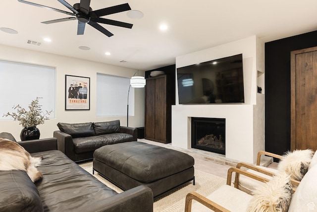 living room featuring recessed lighting, visible vents, a fireplace with raised hearth, and a ceiling fan