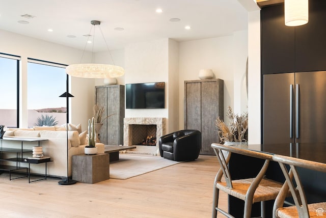 living area with a high end fireplace, visible vents, recessed lighting, and light wood-type flooring