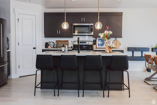 kitchen featuring a breakfast bar, decorative light fixtures, appliances with stainless steel finishes, light countertops, and decorative backsplash