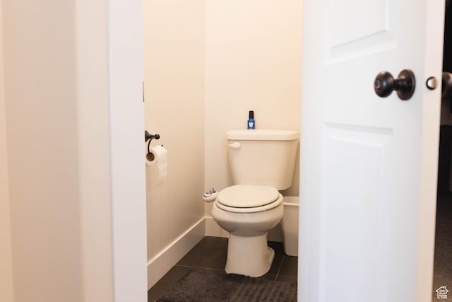bathroom with baseboards, toilet, and tile patterned flooring